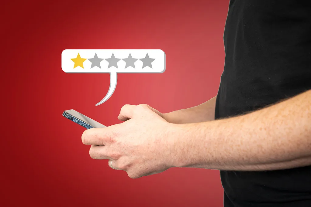 Mão segurando um celular com avaliação de uma estrela