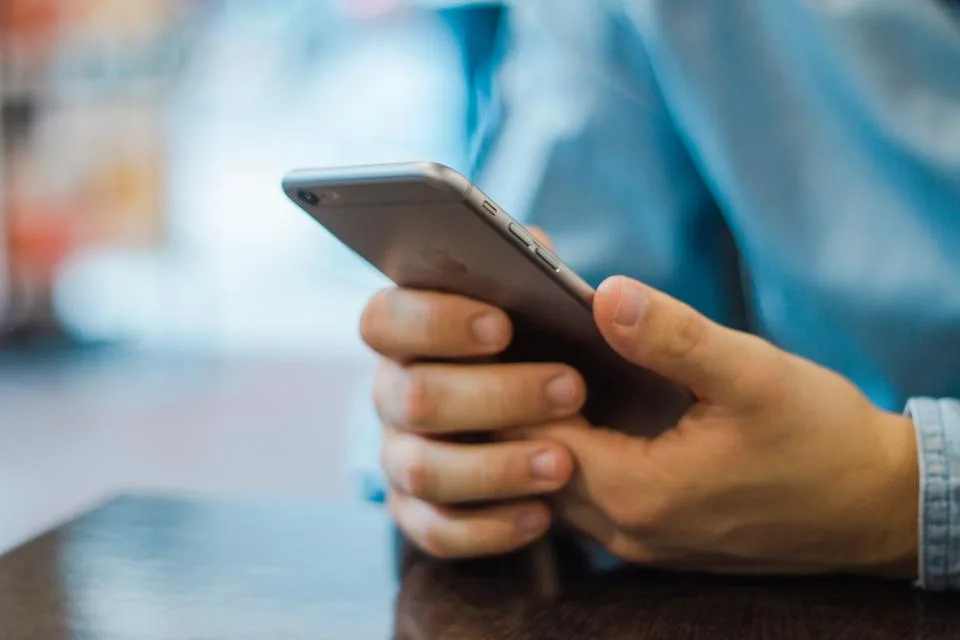 Mãos de uma pessoa segurando um celular e digitando uma mensagem