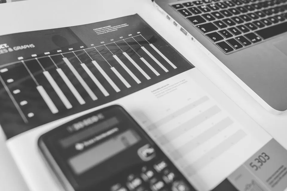 Gráficos impressos, calculadora e notebook sobre a mesa