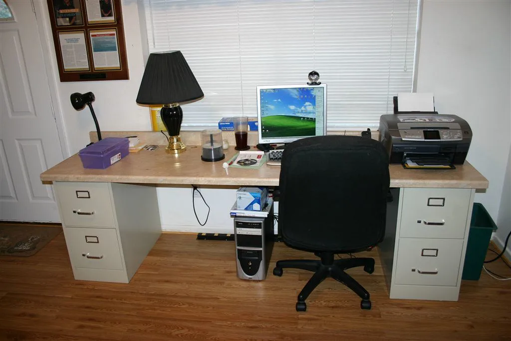 Mesa de escritório com computador, impressora e gaveteiros de arquivo