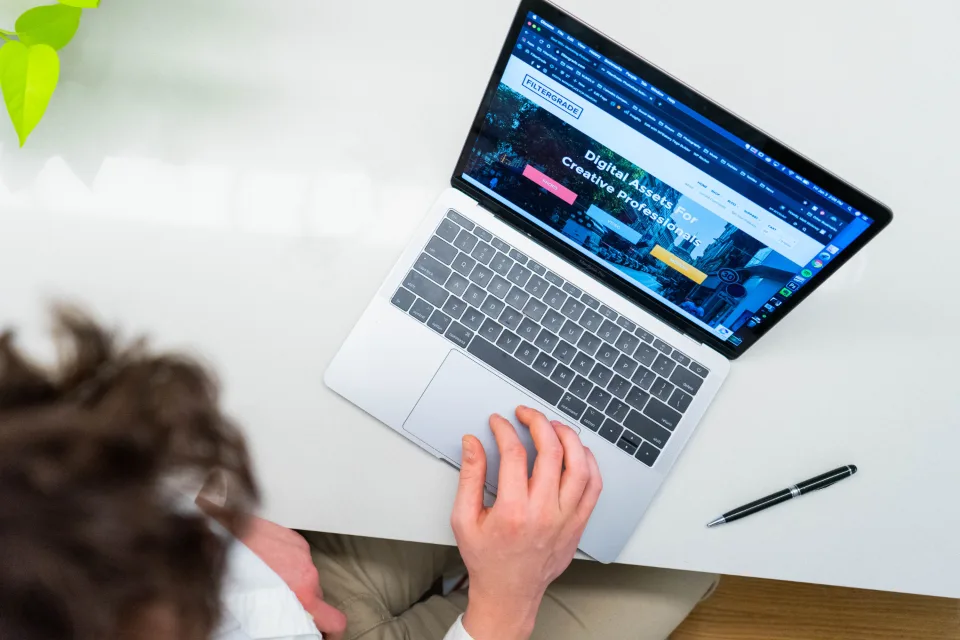 Mãos digitando no notebook com uma página aberta