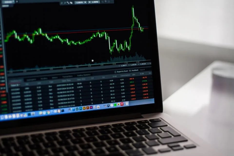 Notebook aberto com gráficos de desempenho na tela, sobre uma mesa de trabalho