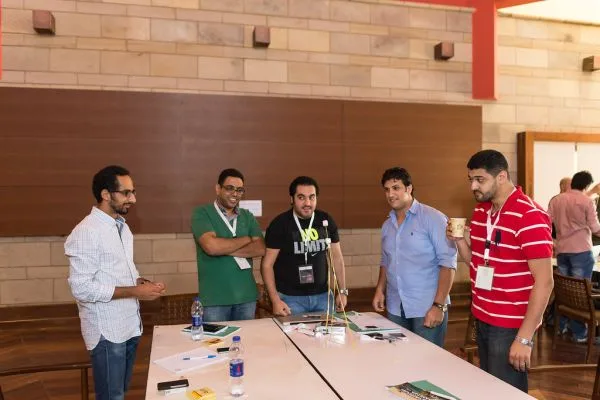 Equipe de startup conversando em pé ao redor de uma mesa de trabalho