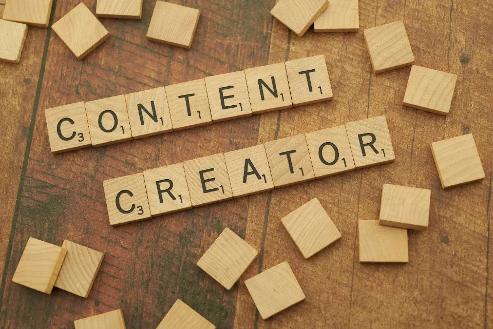 Peças de madeira com letras formando as palavras content creator sobre uma mesa