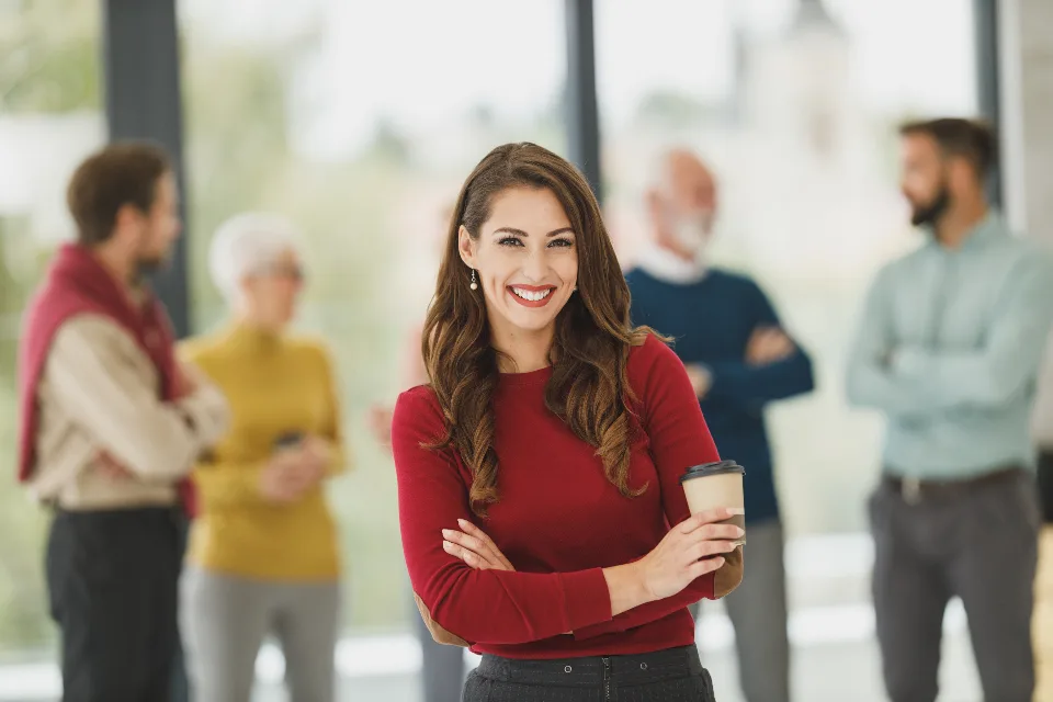 Executiva sorrindo no escritório com colegas ao fundo