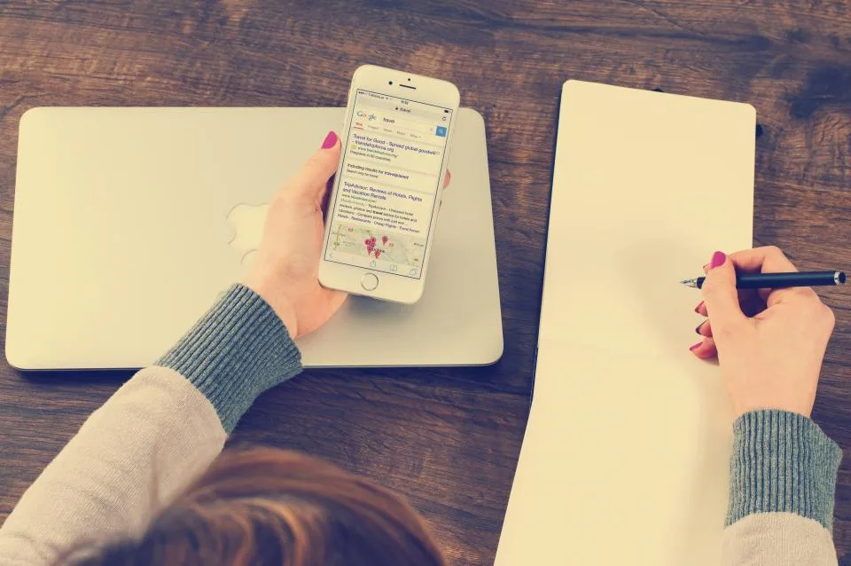 Mãos com celular e caderno de anotações