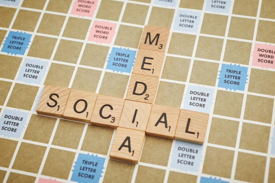 Peças de jogo de palavras formando “social media” sobre o tabuleiro