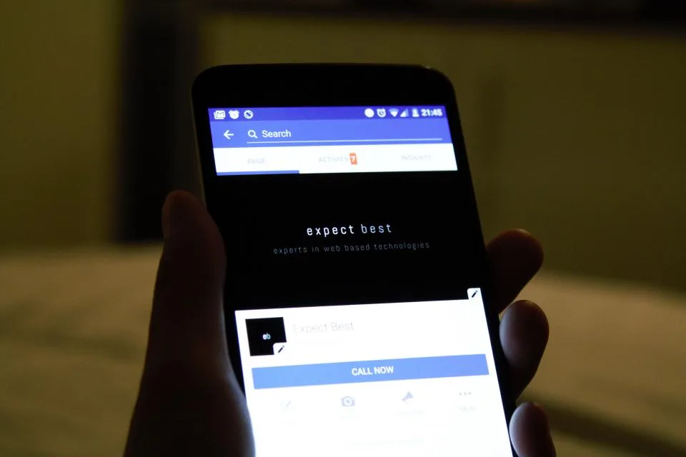 Mão segurando celular com uma página de busca aberta