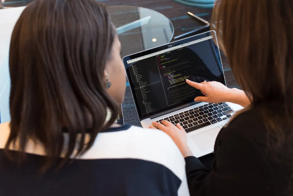 Duas pessoas analisando código em um notebook durante o trabalho em equipe