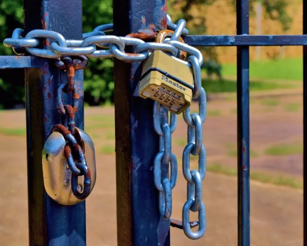 Cadeado de segredo e corrente prendendo um portão de metal em um parque