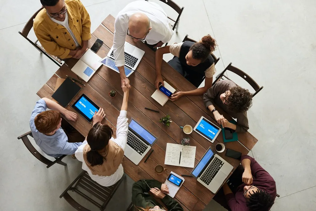 Equipe reunida em volta de uma mesa com notebooks, vista de cima