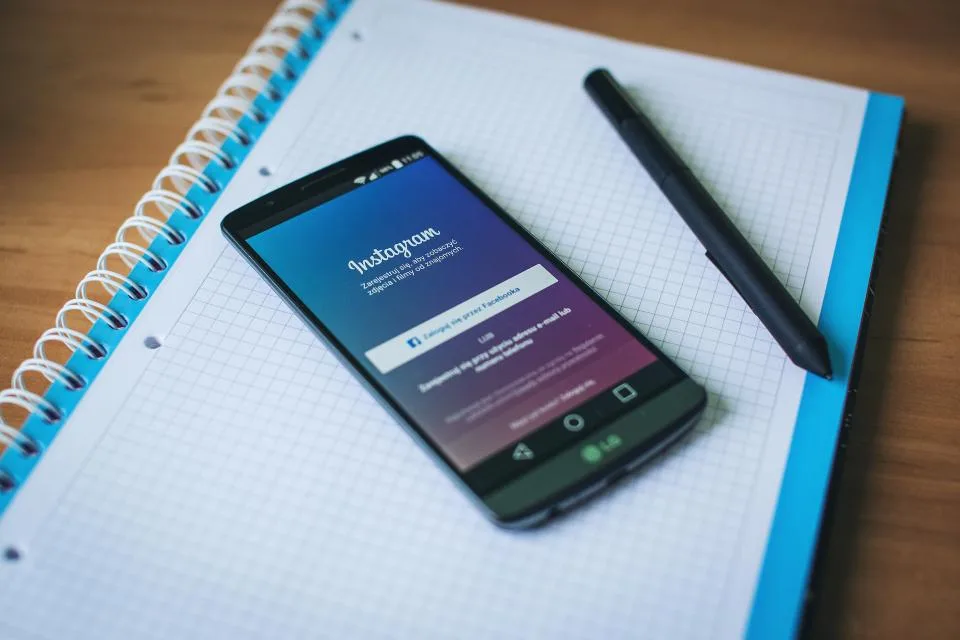 Celular sobre um caderno exibindo a tela de login do Instagram