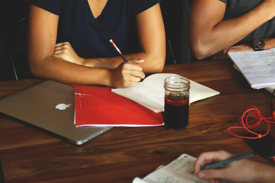 Equipe reunida em volta de uma mesa com cadernos, anotações e um notebook