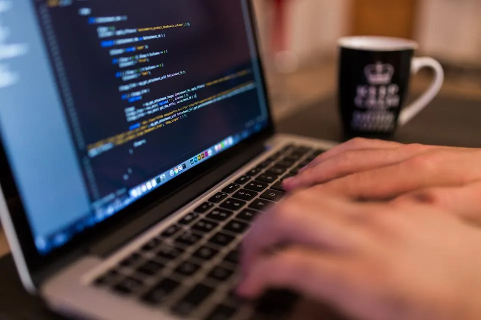 Tela de computador com código de programação em editor de texto, em ambiente escuro