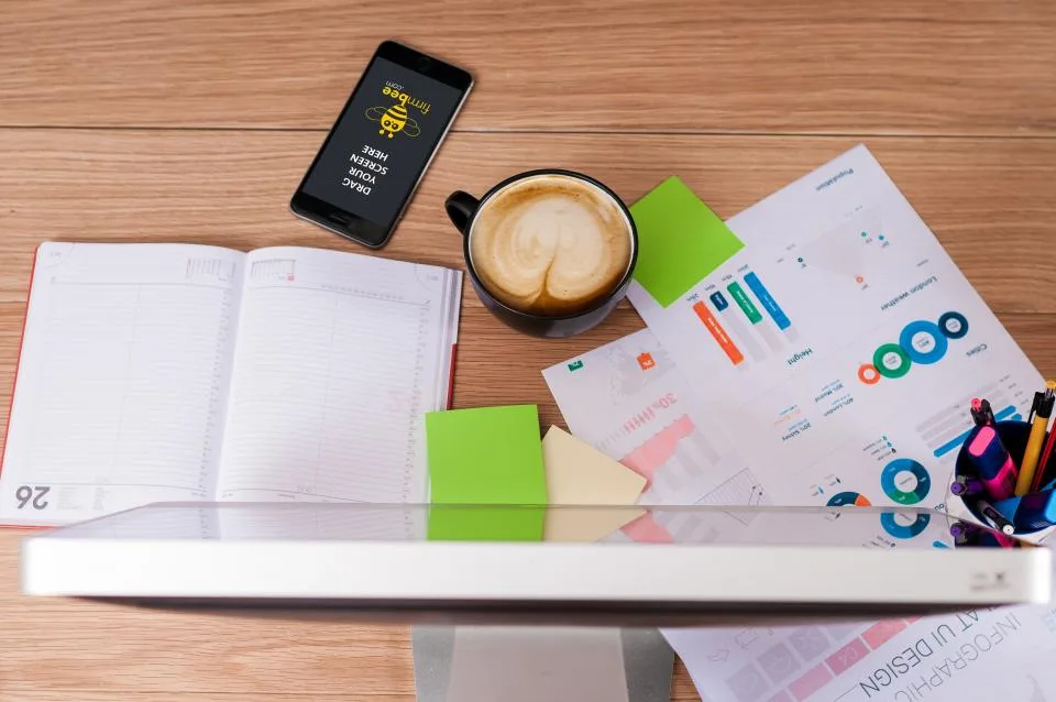 Mesa de escritório com papéis, celular e anotações