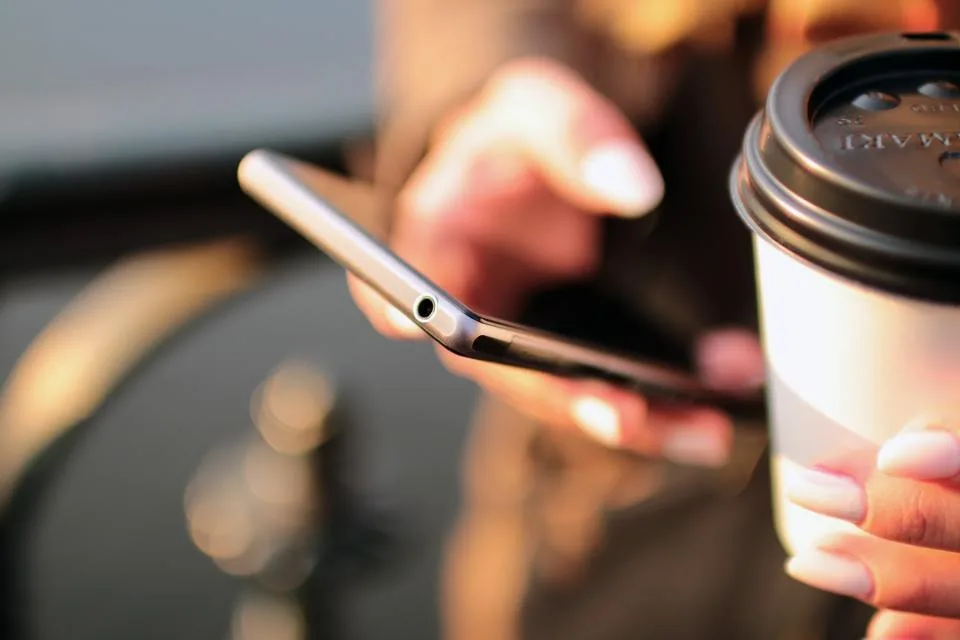 Mão segurando um smartphone com a tela de conversas de mensagens aberta